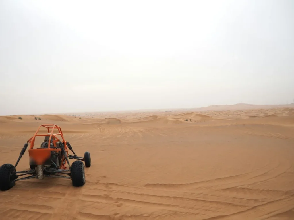 Buggy tout-terrain à l'arceau orange sur les pistes de sable du désert