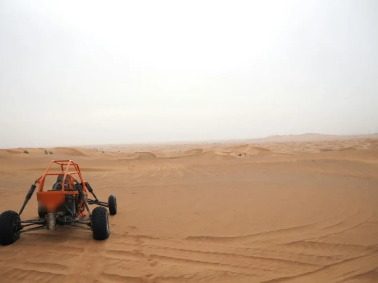 Buggy tout-terrain à l'arceau orange sur les pistes de sable du désert