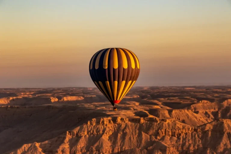 Montgolfière en vol au lever du soleil au-dessus d'un relief désertique